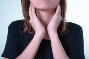 Mal di gola: cause, rimedi e quando preoccuparsi Close-up of a woman touching her neck, possibly indicating discomfort or throat pain.